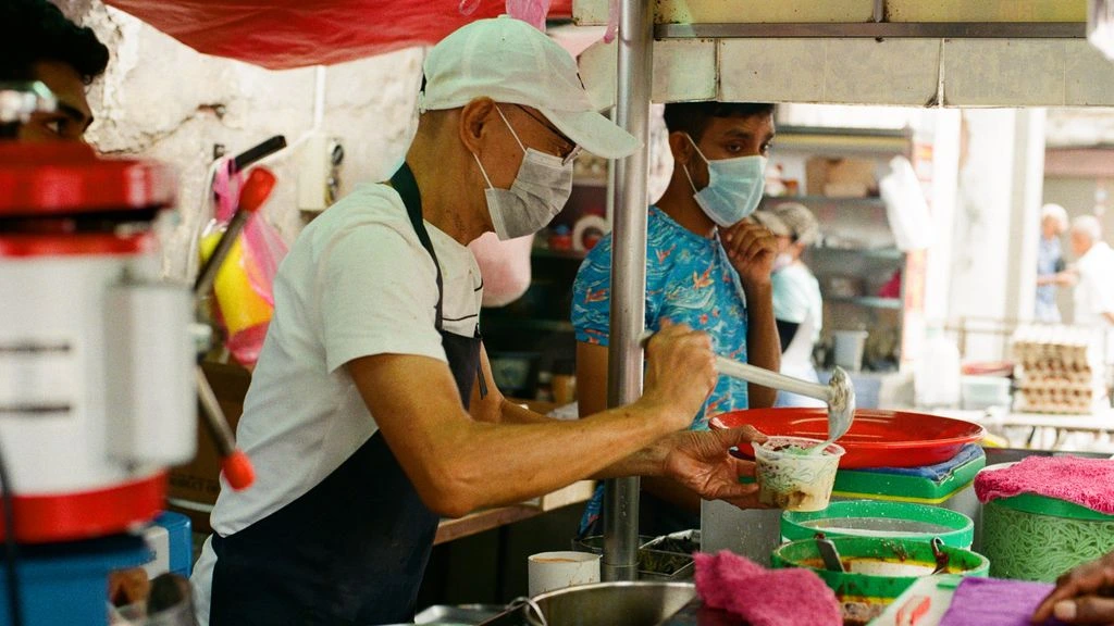 The seven-person editorial team at a morning meeting in a George Town kopitiam.